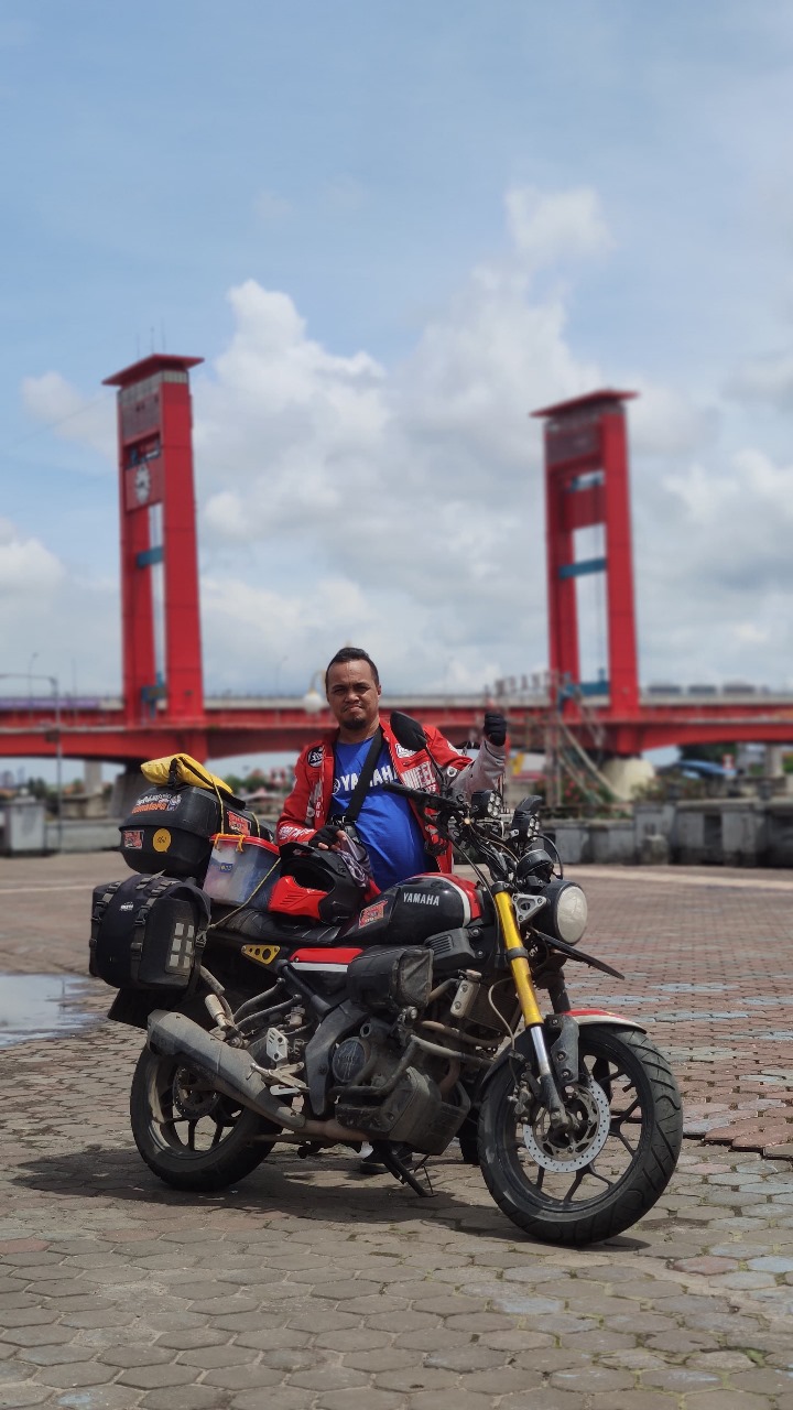 Djoe Avarell mengabadikan momen dengan latar belakang Jembatan Ampera saat Long Ride 360 derajat Sumatera ketika melintas di Kota Palembang. FOTO: ISTIMEWA. 