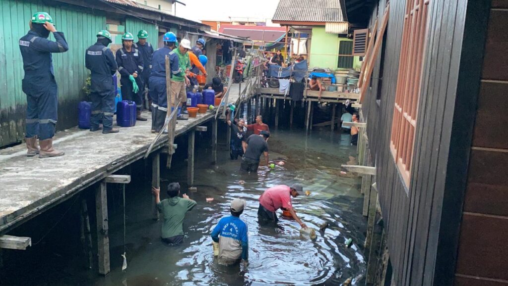 Petugas mengambil sisa minyak yang disebut berasal dari pembersihan pipa kilang minyak Balikpapan. FOTO: ISTIMEWA 