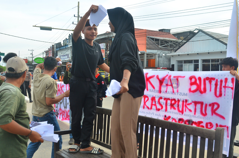 Aksi parodi saweran GMNI Kutim dan BEM Stiper Kutim, di simpang tiga Jalan Pendidikan, Sangatta, Selasa, 18 Februari 2025. FOTO: CHE HARSENO-KALTIMKECE.ID